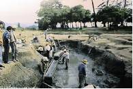 大極殿造営直前の建築資材運搬用の運河跡発掘風景。後ろは、大宮土壇